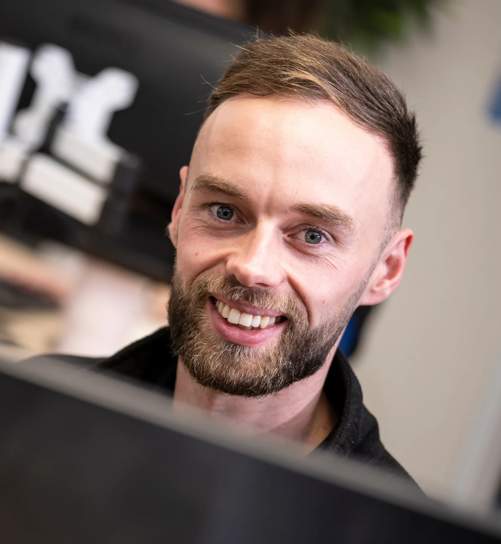 Smiling Joe, support engineer from DISConsulting IT looking up from his screen in the office, offering friendly and approachable customer service.
